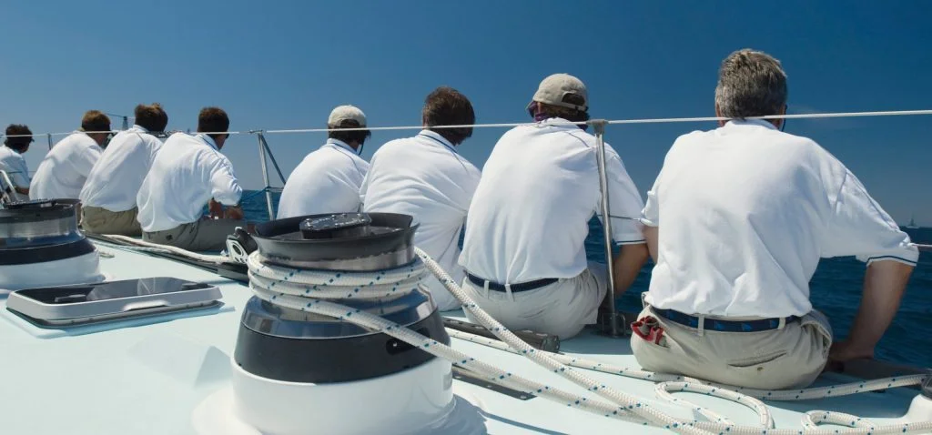 Group of yacht crew sat on the deck in a line